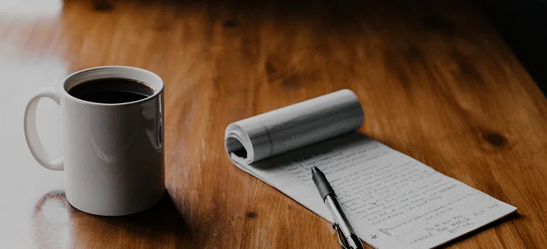Cup of coffee and paper with a pen
